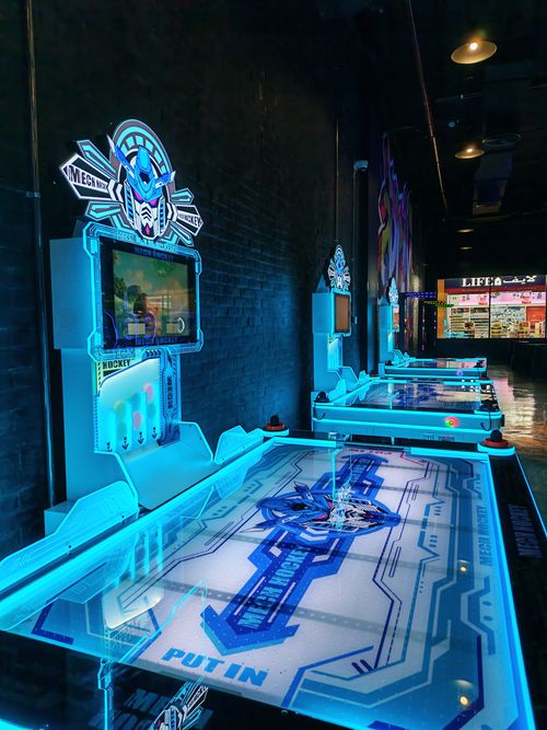 Free Vibrant neon-lit air hockey machines in a modern arcade setting, ready for action. Stock Photo