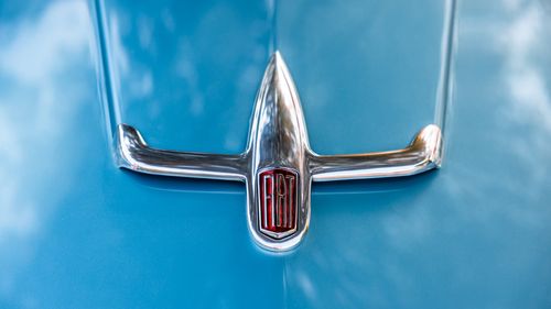 Free Vintage car emblem with a sleek design on blue background, classic car detailing. Stock Photo