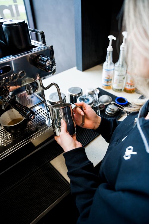 Free Barista steaming milk for a fresh cup of espresso in a modern cafe setting. Stock Photo