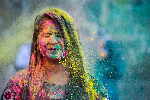 Free Vibrant portrait of a woman enjoying Holi festival, covered in bright powder colors. Stock Photo