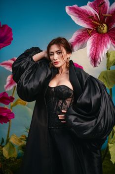 Elegant woman in black fashion outfit with vibrant oversized flowers.