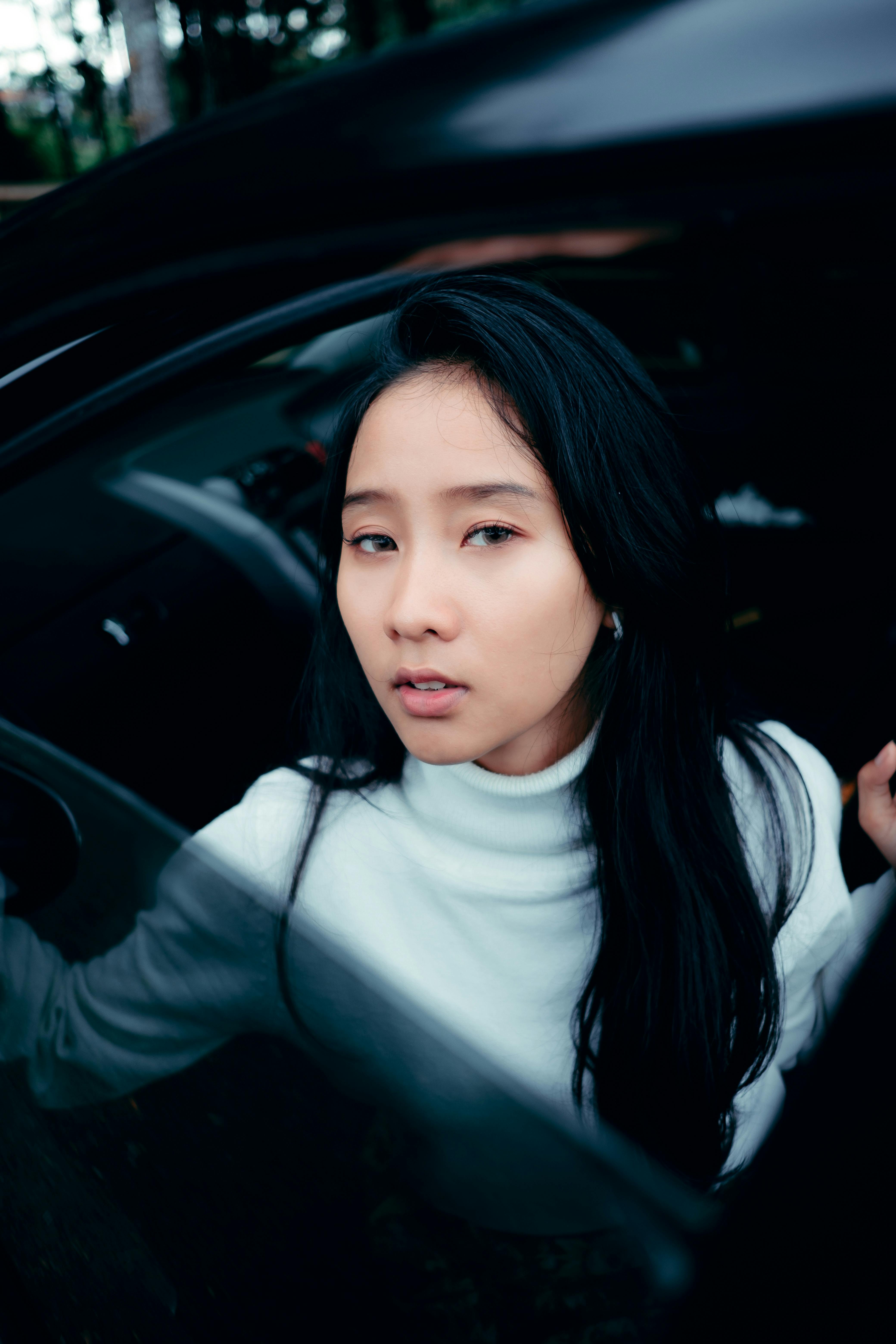 Portrait of a fashionable woman stepping out of a car in a city environment. Cool tones enhance the modern vibe.