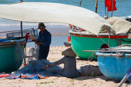Free A glimpse of traditional fishing life on a Vietnamese beach with colorful boats and nets. Stock Photo
