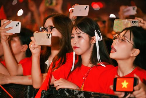 Free Group of young women in red shirts capturing a live event with their smartphones. Stock Photo