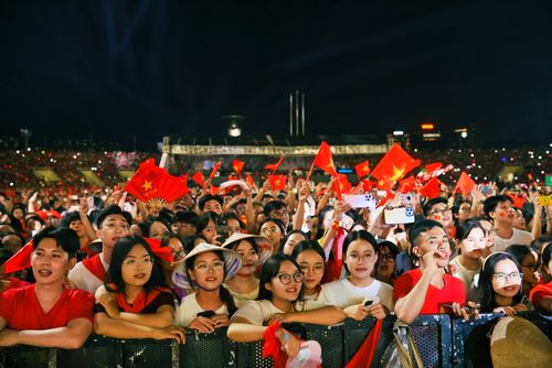 Free Excited crowd at a nighttime concert waving red flags, capturing the lively spirit of an event. Stock Photo