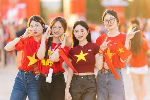 Free Group of young women celebrating outdoors with red shirts and flags. Stock Photo