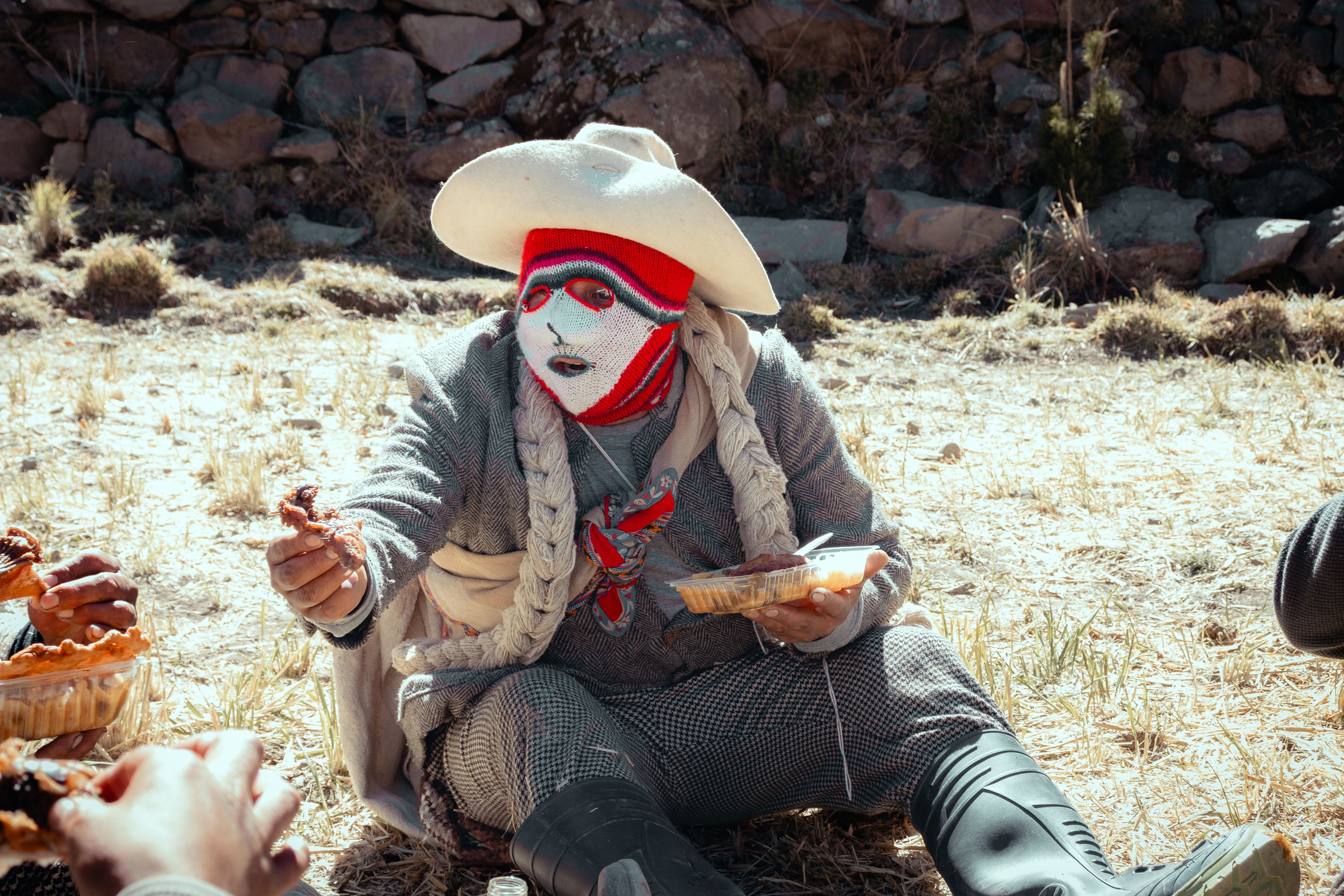 Fotomural Una persona con vestimenta tradicional disfruta de la gastronomía local al aire libre durante una celebración festiva en Arequipa, Perú.