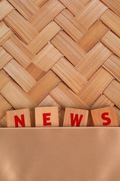 Free Close-up of wooden blocks spelling 'NEWS' against a woven wooden background. Stock Photo
