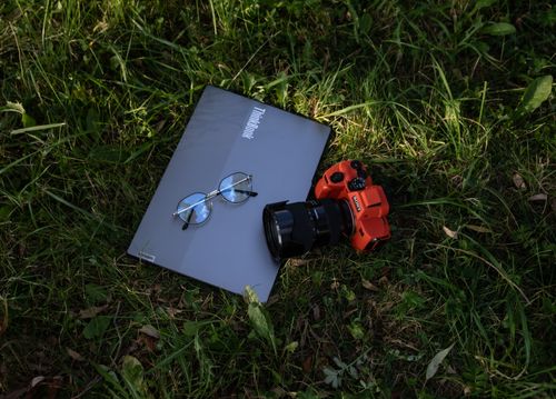 Free A camera, laptop, and glasses resting on grass, ideal for tech and nature themes. Stock Photo