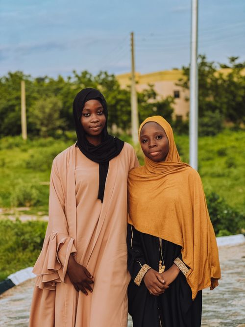 Free Two women in hijabs standing together in a green outdoor setting. Stock Photo