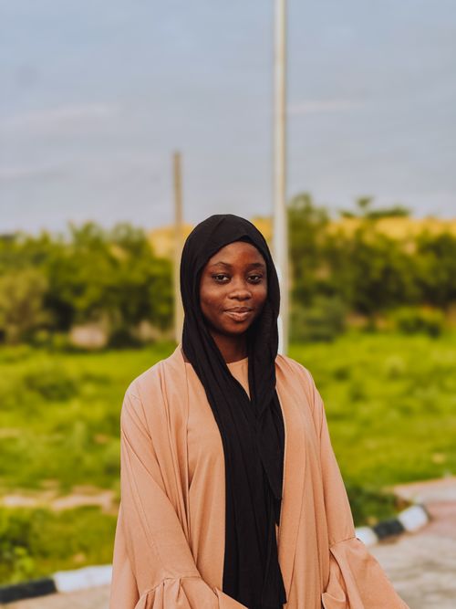 Free A joyful young woman in a hijab stands outdoors, capturing a serene and warm moment. Stock Photo