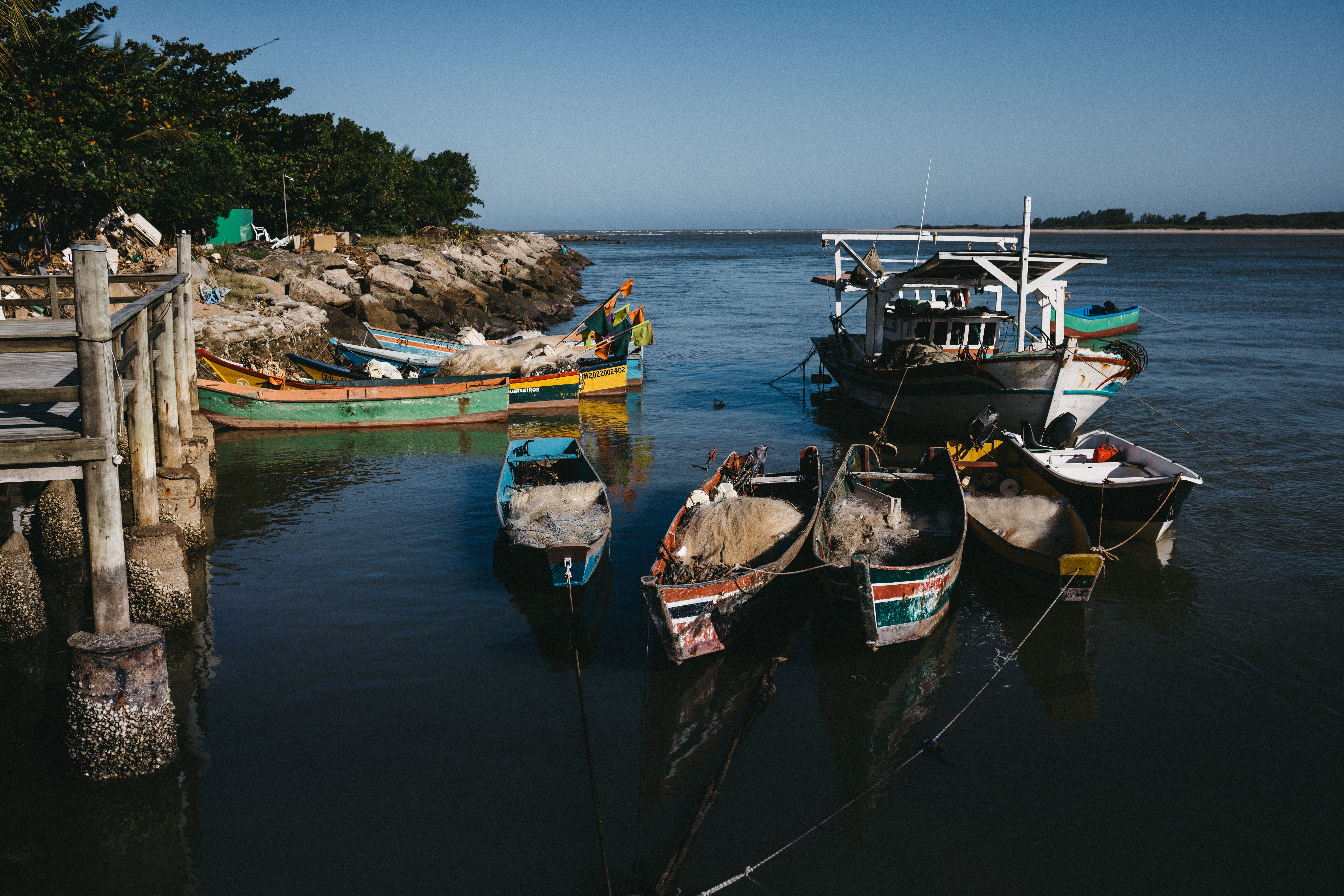 A serene view of colorful fishing boats docked in a Brazilian harbor on a sunny day.