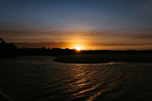Free Captivating sunset with vivid colors reflecting on calm beach waters, exuding tranquility and beauty. Stock Photo