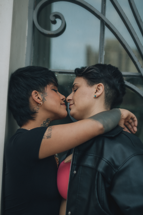 Free Close-up of a couple embracing next to a decorative window, expressing love and intimacy. Stock Photo