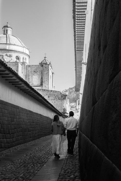 Free A couple strolls through a narrow alley in Cusco, Peru, beside Inca stone walls. Stock Photo