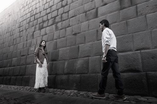 Free A man and woman face each other by a stone wall, captured in a moody monochrome setting. Stock Photo