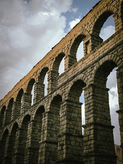 Free Classic viewpoint of the ancient Segovia Aqueduct, captured in dramatic lighting with clouds. Stock Photo