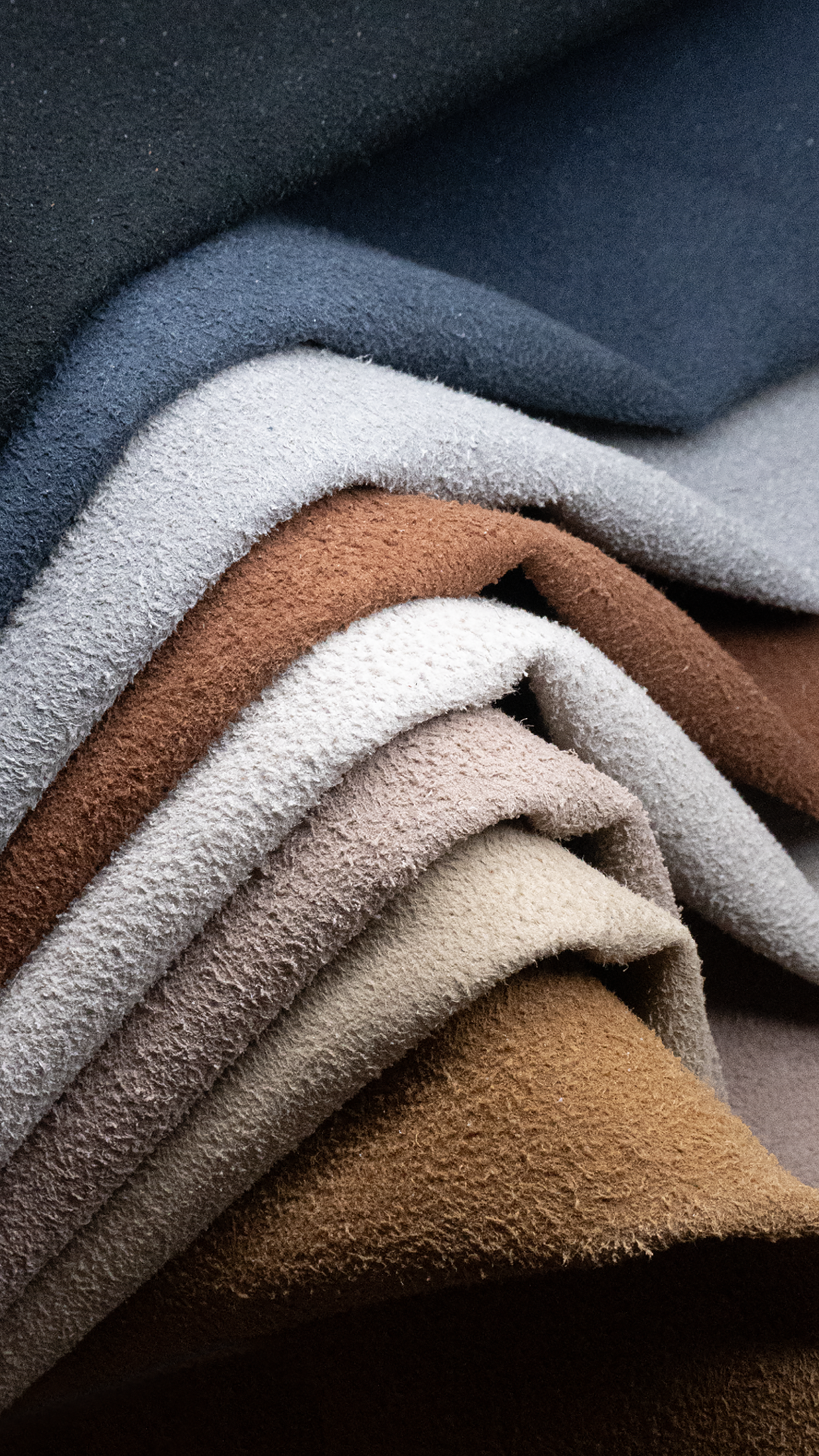 Detailed image of stacked textured fabric in various earthy hues, perfect for textile design. - best fabric for ladies dresses in Pakistan