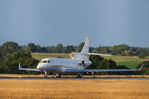 Free A sleek private jet readies for takeoff on an English runway, surrounded by lush fields. Stock Photo