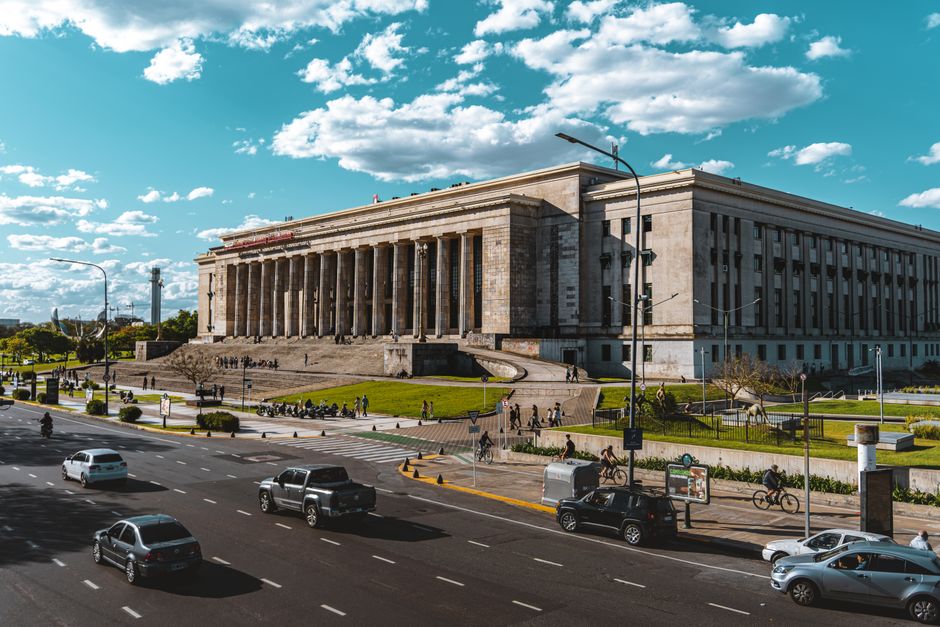 Vista de la Universidad de Buenos Aires desde una calle, que captura la vida de la ciudad en un día soleado.