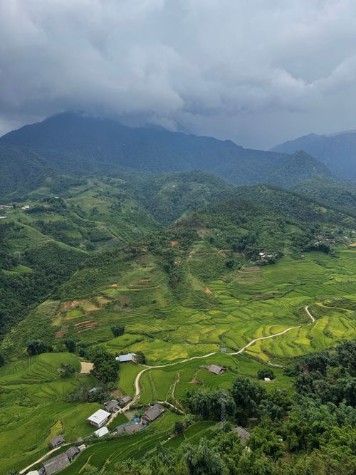 Free Explore the breathtaking aerial view of vibrant green rice terraces amidst mountainous landscapes under moody skies. Stock Photo