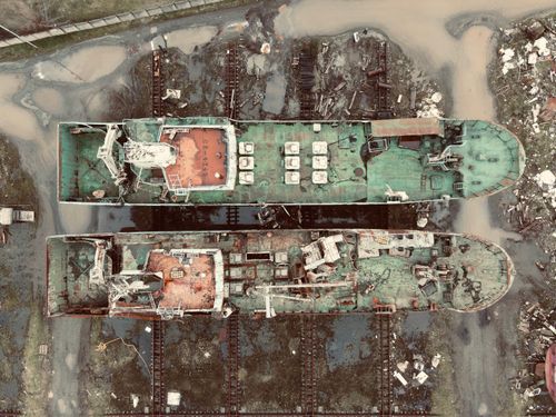 Free Two abandoned ships with rust and decay in a desolate shipyard seen from above. Stock Photo