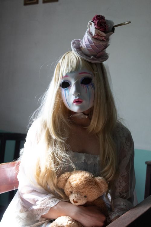 Free Mysterious figure in mask holding teddy bear, creating eerie mood. Stock Photo