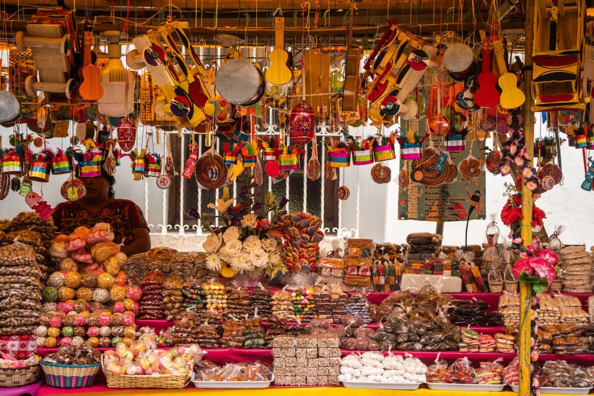 Vibrant Mexican market stall displaying traditional sweets and handmade crafts, offering a rich cultural experience.
