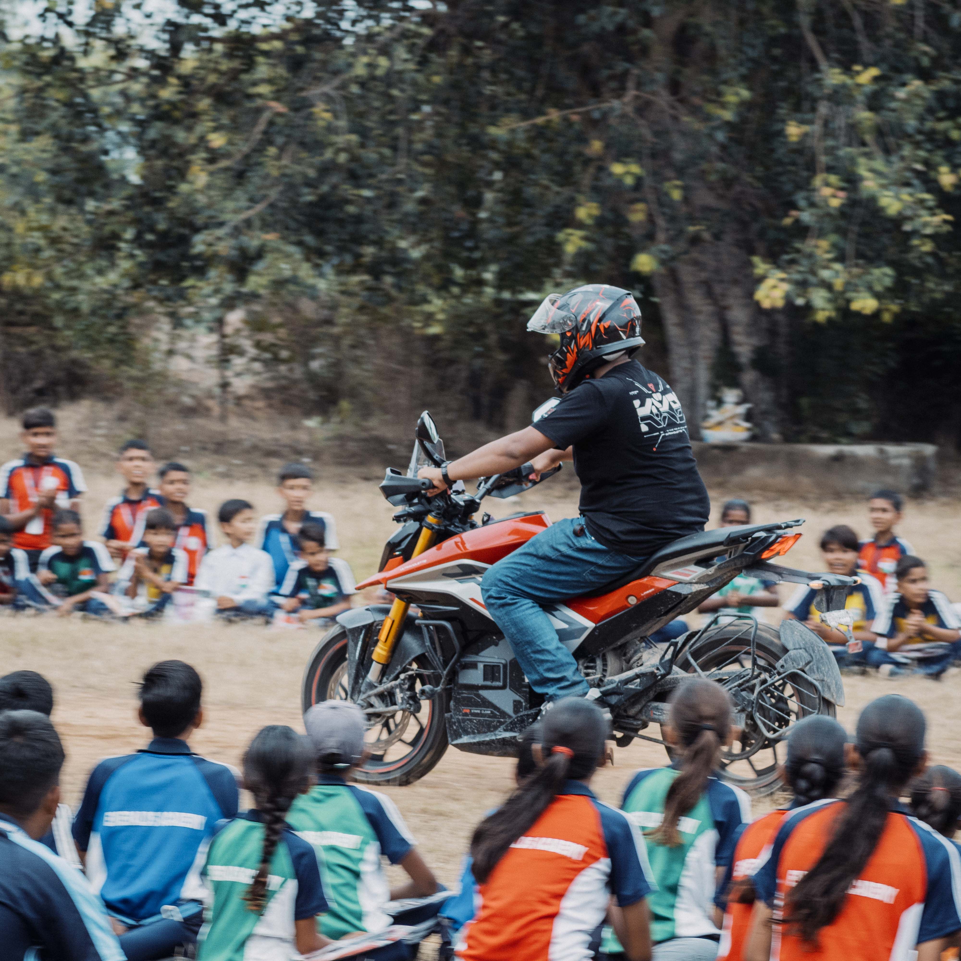 Motorcyclist showing skills on an electric bike in front of children in Jaipur, India.
