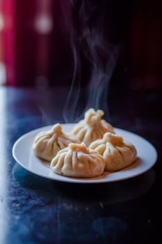 Appetizing steamed dumplings with steam rising, served on a white plate.
