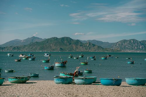 Free Scenic view of round basket boats on sandy beach with stunning mountain backdrop, ideal for travel concepts. Stock Photo