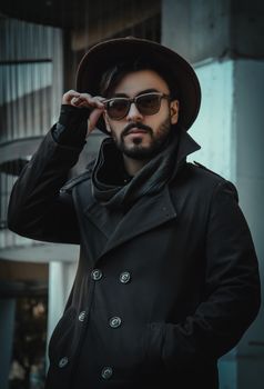 一位时尚男子戴着太阳镜，穿着外套，站在德黑兰的户外