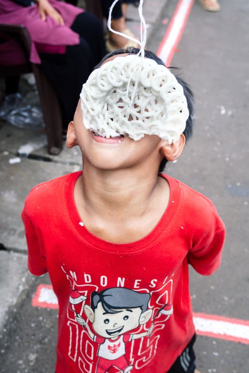 Free A child enjoying kerupuk snack at a street game in Jakarta, Indonesia. Stock Photo
