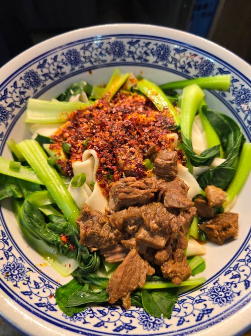 Free Delicious spicy beef noodle bowl with bok choy and chili flakes in a decorative dish. Stock Photo