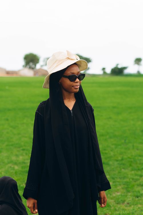 Free Stylish woman wearing a hat and shades in an open green landscape. Stock Photo