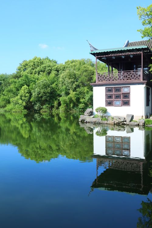 Free Serene reflection of a traditional Chinese pavilion by a calm lake surrounded by lush greenery. Stock Photo