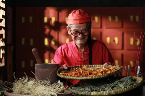 Free Senior herbalist preparing traditional remedies with dried herbs in Jakarta, Indonesia. Stock Photo
