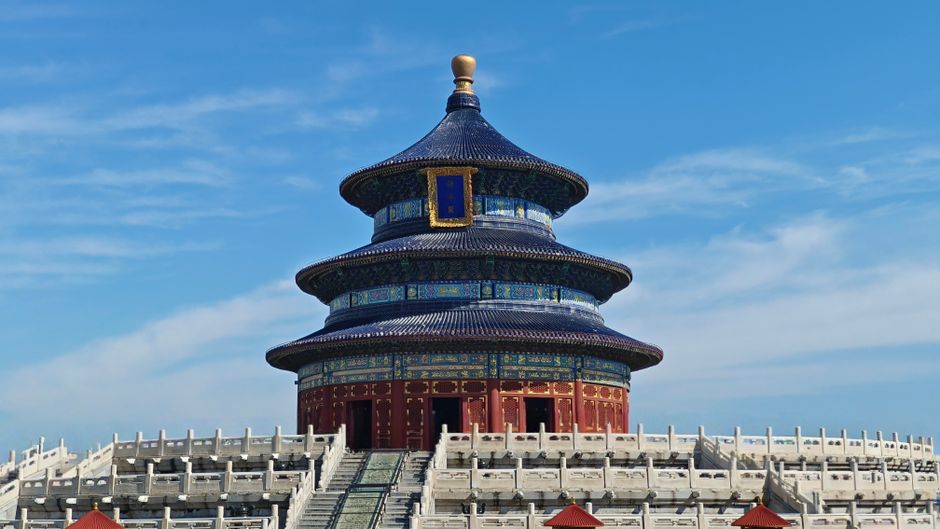Panoramic view of the iconic Temple of Heaven in Beijing under a bright blue sky, showcasing traditional Chinese architecture.
