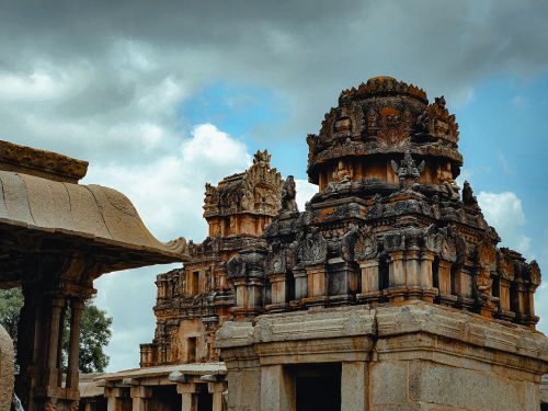 Free Intricate stone carvings on ancient temples in Hampi, Karnataka, under a cloudy sky. Stock Photo