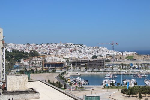 Free Scenic view of Tangeri harbor with boats, city buildings, and cranes under a clear blue sky. Stock Photo