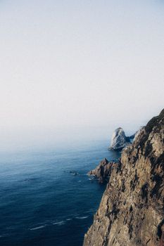 Stunning view of rugged coastal cliffs meeting the vast ocean under a clear sky.