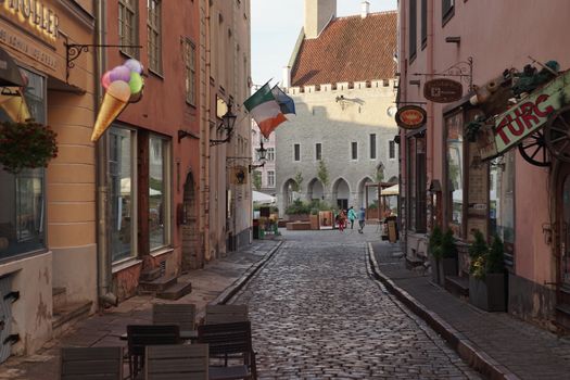 A picturesque cobblestone street in Tallinn's Old Town with colorful buildings and an Irish flag.