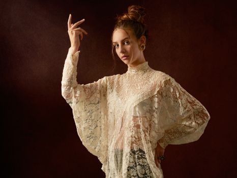 深色背景下，一位身着优雅蕾丝服装的年轻女子自信摆姿，其肖像令人惊叹