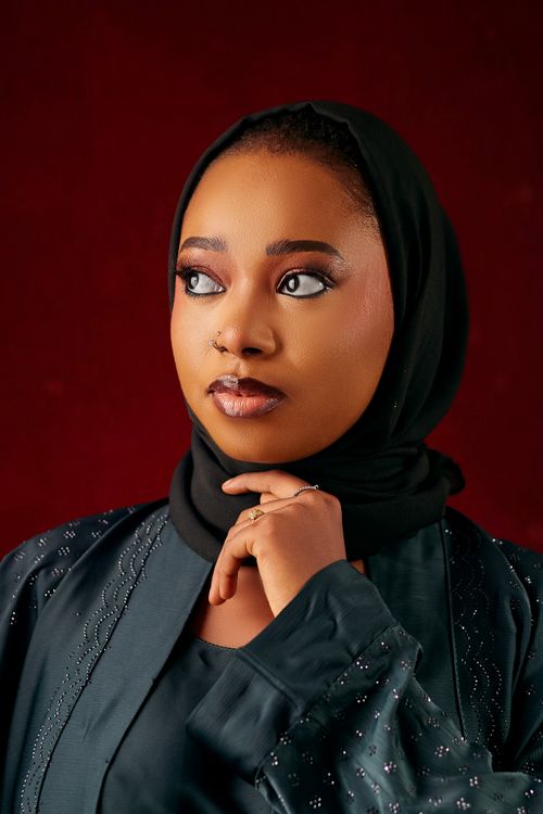 Free Striking portrait of a woman wearing a hijab against a red backdrop, showcasing elegance and poise. Stock Photo