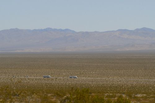 Free Vast California desert with distant road and mountains, showcasing remote travel. Stock Photo