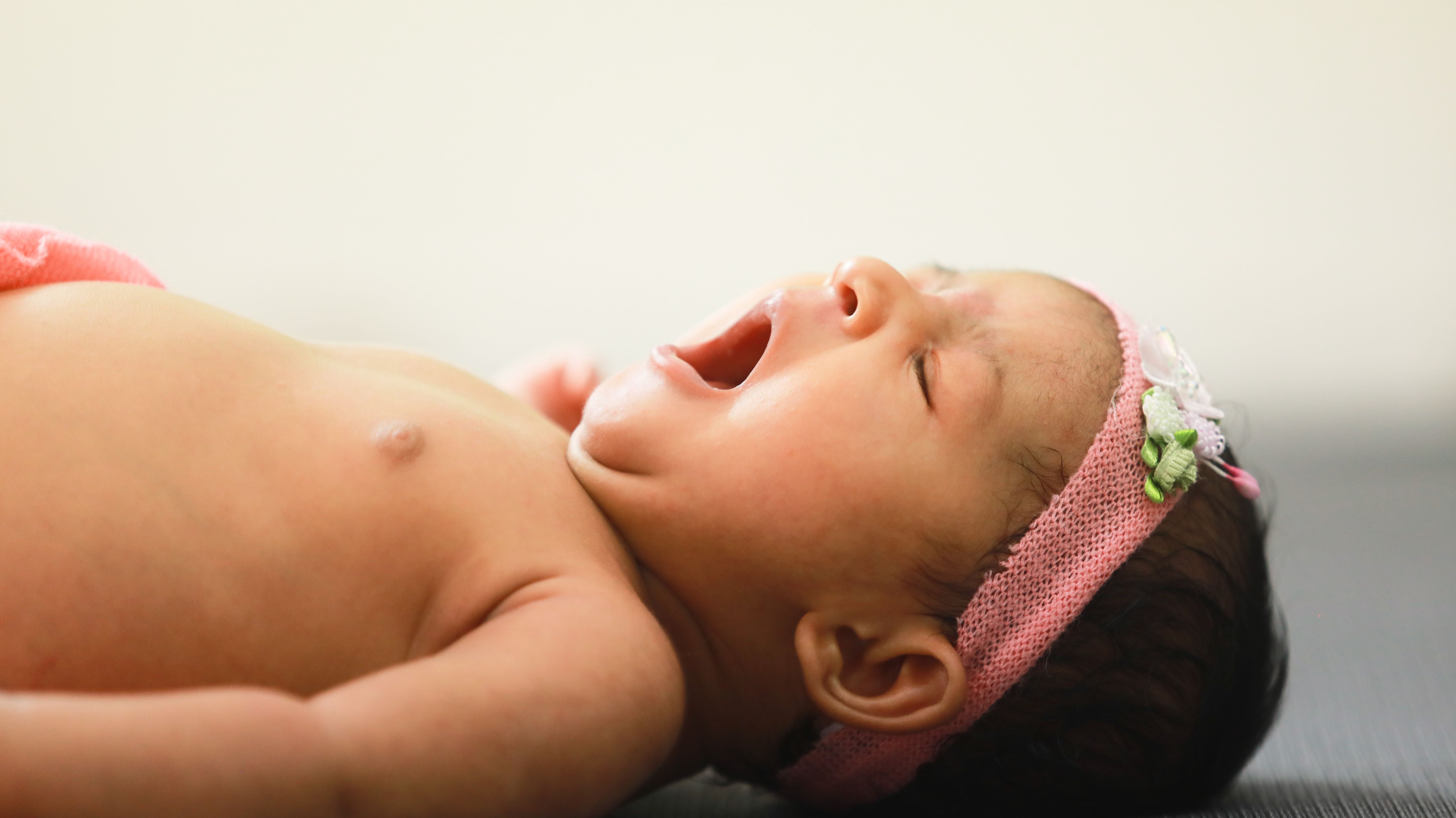 Mother gently holding newborn baby in hospital setting, showcasing warmth and love.