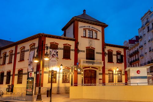 Free Historic Escuela de Artesanos building in Valencia at blue hour with warm urban lighting. Stock Photo
