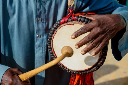 Free Detailed view of a person playing a traditional Nigerian drum with vibrant handwork details. Stock Photo