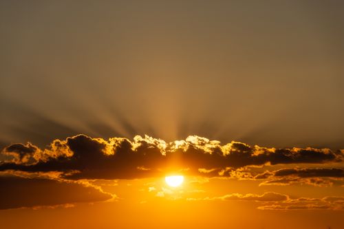 Free A stunning sunset with bright sun and dramatic clouds, creating a golden sky radiating warmth. Stock Photo
