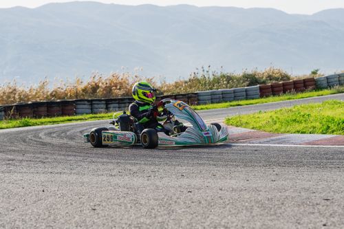 Free High-speed kart racing on an outdoor track with scenic mountainous background. Stock Photo